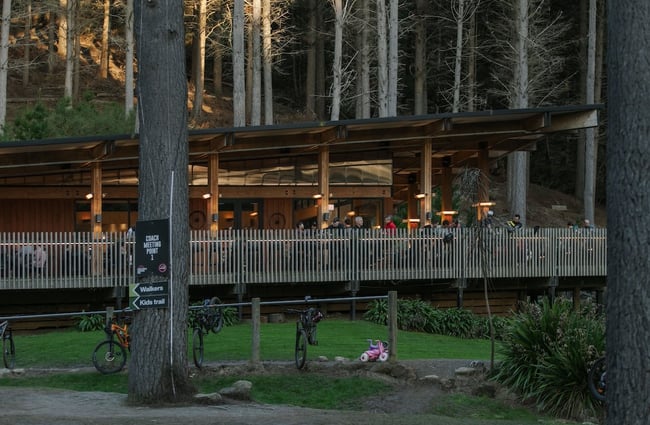 People dining on the café deck, lit up in the evening dark, at Christchurch Adventure Park.