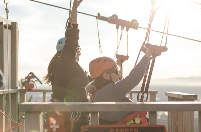 Two women harnessed in and waiting to ride a zip line at Christchurch Adventure Park.