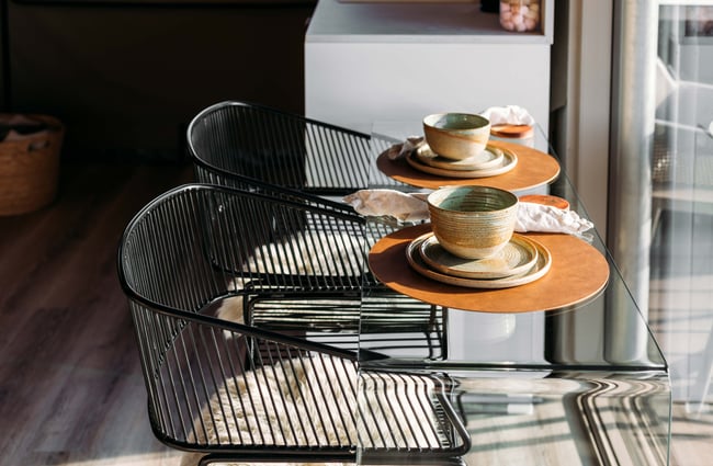 Tables and chairs with bowls and plates looking out towards a window.