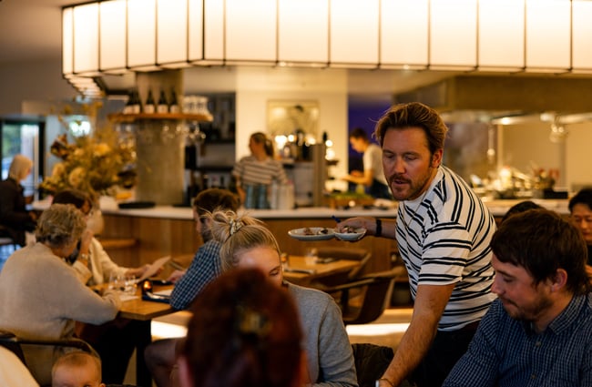 Earl owner Tom serving plates of food to customers at his restaurant in Christchurch