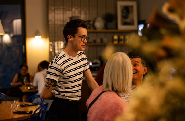 Waiter talking happily to customers at Earl in Christchurch