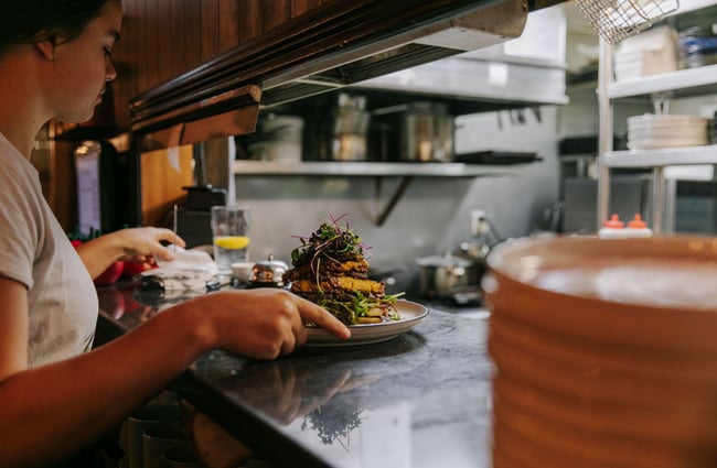 Waitress collecting meal from the kitchen pass.