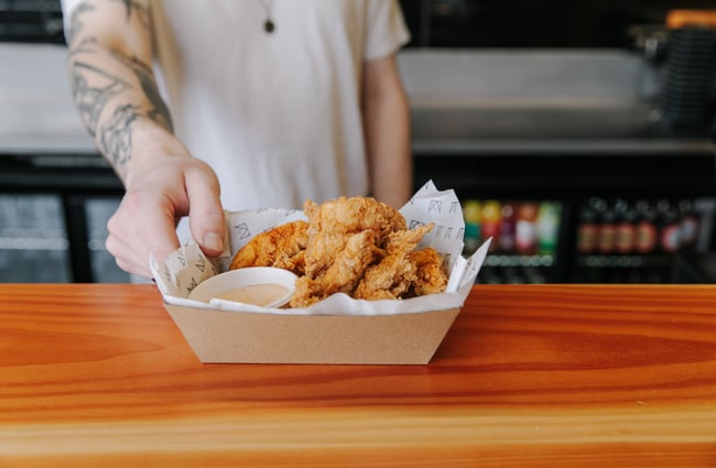 Close up of man holding a box of fried chicken pieces from Empire Chicken in Christchurch.