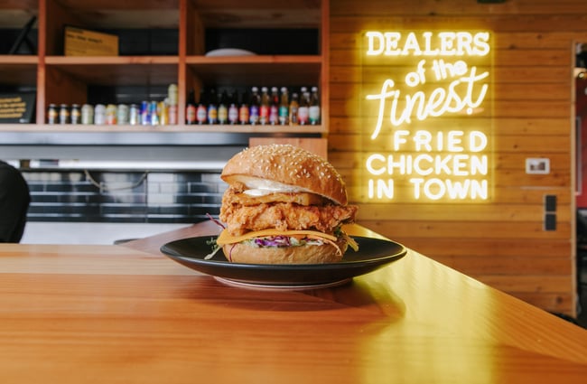 Empire Chicken burger on a plate with neon sign behind.