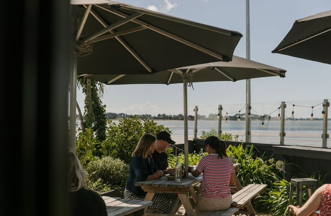 People sitting outside near the estuary on a sunny day.