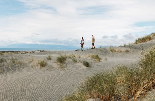 Two men walking along the beach on a sunny day.