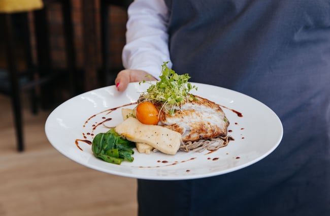 A wait staff holding a plate of food Fiddlesticks in Christchurch.