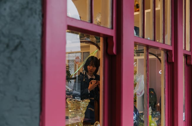 Looking through the window to woman browsing the gallery.