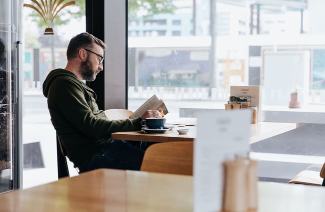 Man reading a book while having a coffee at Foundation Café in Christchurch.