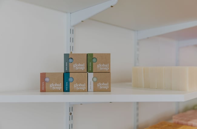 Global Soaps wrapped in cardboard packaging on a shelf.