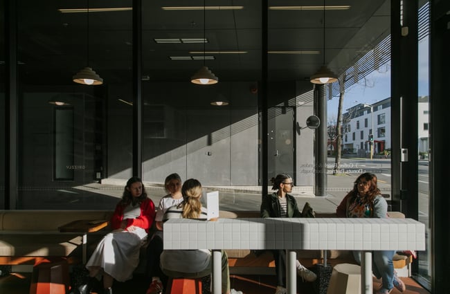 People sitting in a sunny window at a cafe.