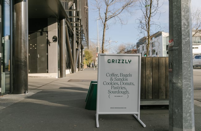 A Grizzly Baked Goods sandwich board on a footpath.