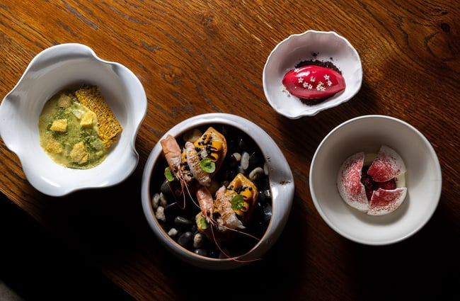 Birds eye view of plates of food on a wooden table at Inati restaurant in Christchurch.