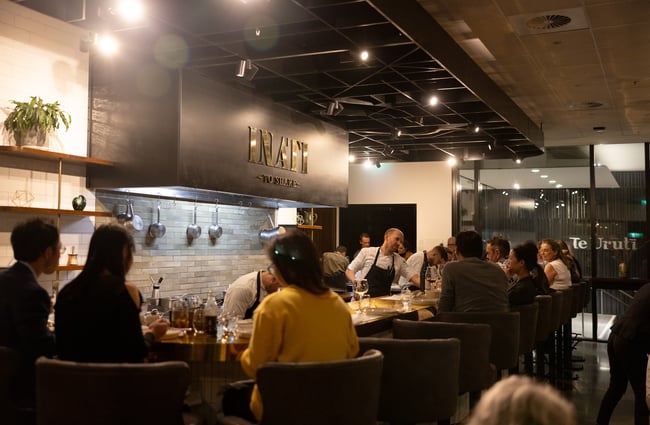 People sitting around the open kitchen at Inati as chefs work.