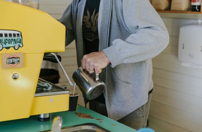 Barista steaming milk in stainless steel jug at Java Hut, Māpua.