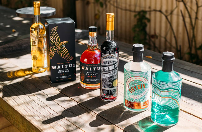 Bottles of spirits lined up on a wooden table on a sunny day.