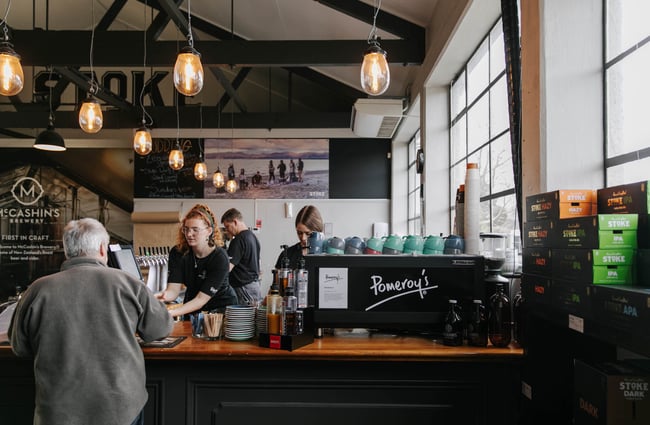 Woman serving a man at the till at McCashins Brewery.