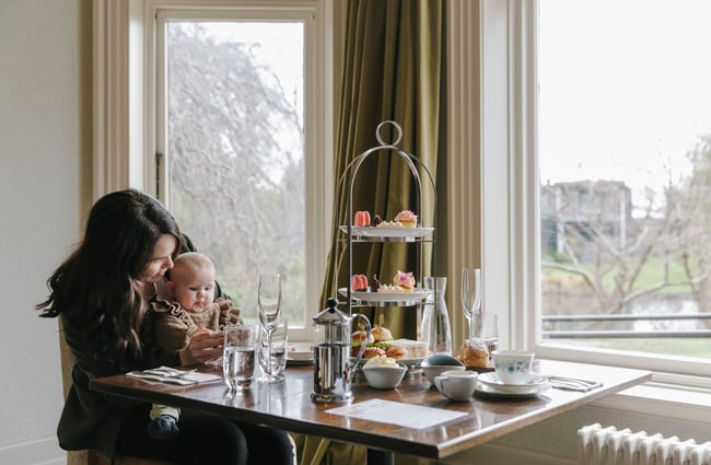 Mum and baby sitting at a table next to the window.