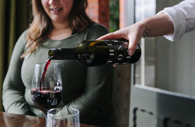 Red wine being poured into a glass at Mona Vale in Christchurch.