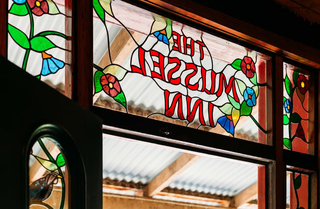 Coloured glass above a door that says 'Mussel Inn'.