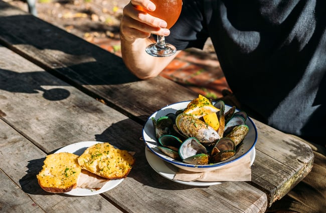 A close up of mussels in a bowl with a side of toasted buttered bread.