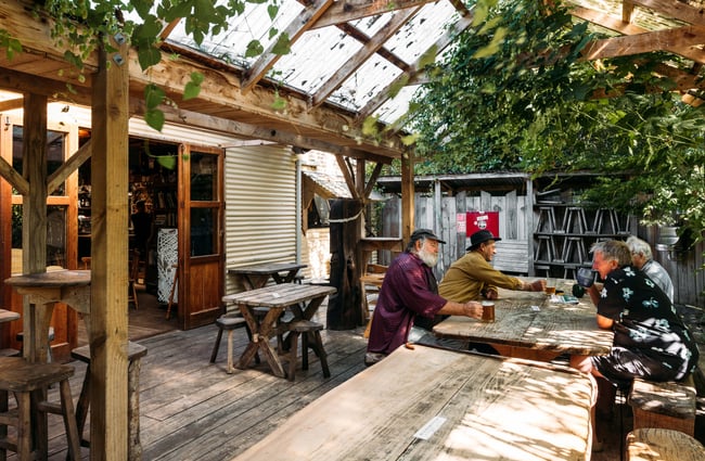 Men sitting around wooden tables outside Mussel Inn.