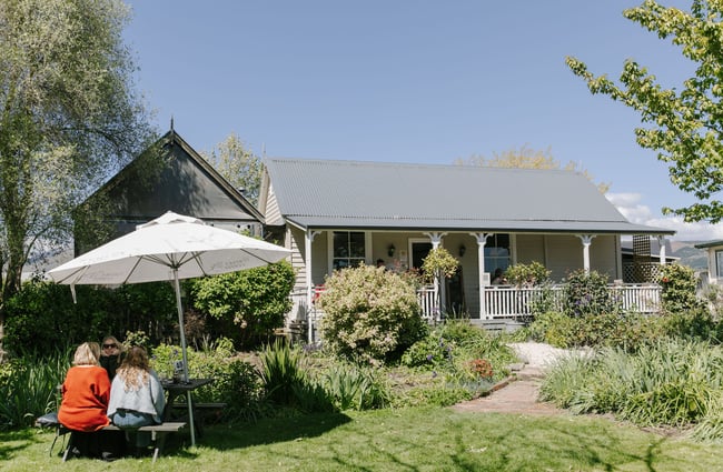 Outdoor area with old cottage in the background at Old Factory Corner, Nelson Tasman.