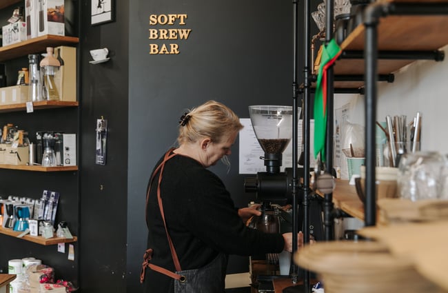 A lady standing at the coffee grinder at the Rabbit Island Coffee Co.