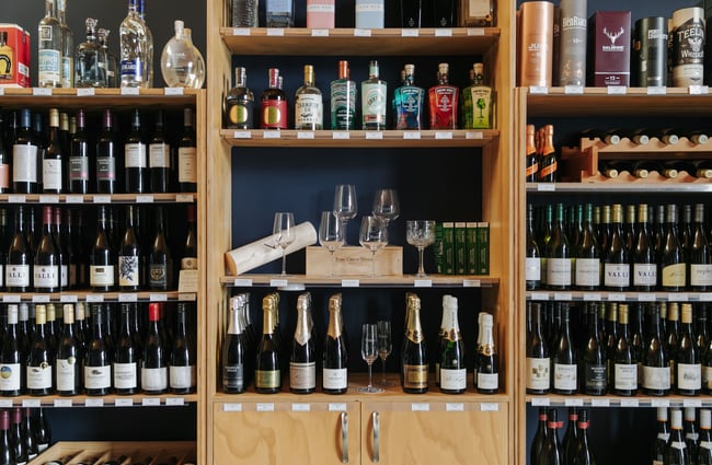 A close up of wine bottles on shelves.