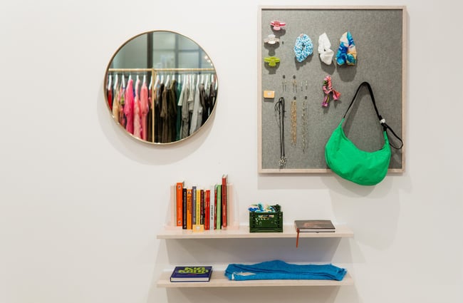 A circular mirror and items for sale on the wall and two small shelves at Ruby clothing store in Central Christchurch.