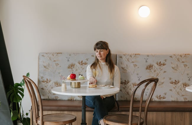 A woman holding a glass of champagne next to sweet cakes.