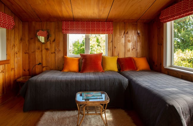 A bedroom with two beds decorated in dark grey quilts.