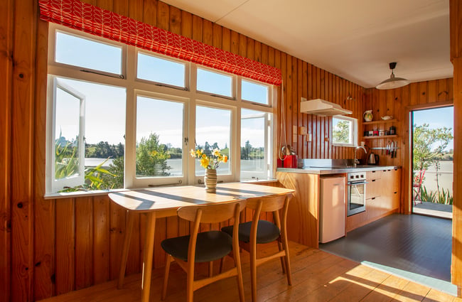 Sun streaming into a kitchen decked out with wooden floorboards and finishings.