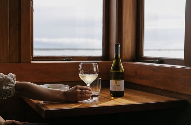 Woman holding a glass of white wine at Boat Shed Cafe.