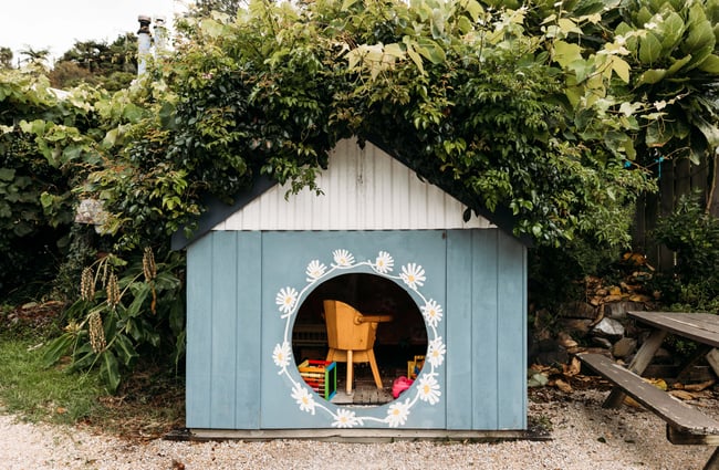 A little cubby house for kids painted in blue and with flowers.