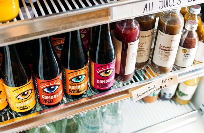 A close up of bottles of drinks in a fridge.