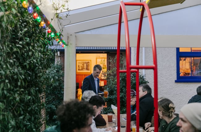 Man holding pint in the outdoor seating area.