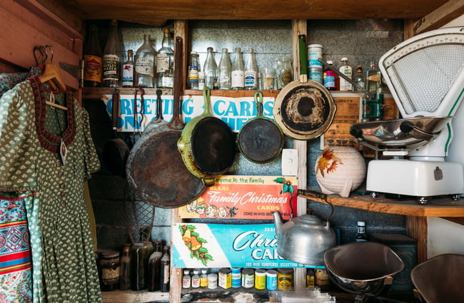 Old pans hanging up alongside vintage dresses.