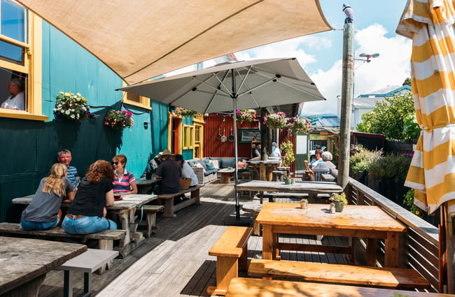 Customers sitting at outdoor tables and chairs on a sunny day.