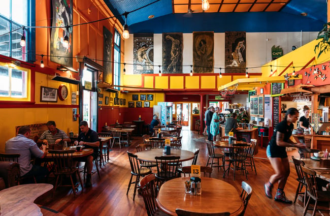 Customers sitting at tables inside a colourful cafe.