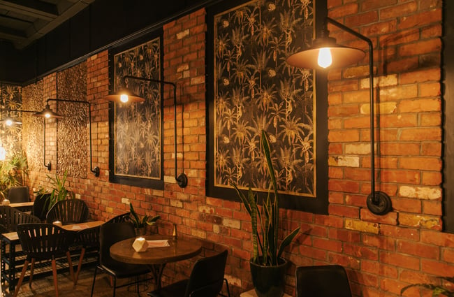 A larger brick wall with works of art on display.