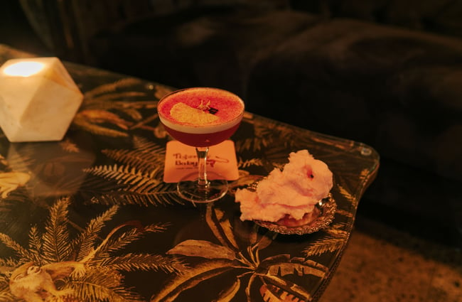 A close up of a pink cocktail on a table.