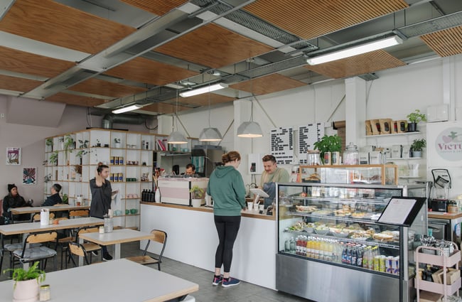 A customer ordering at the counter inside Victus Coffee.