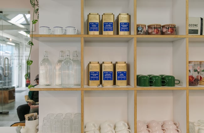 White and wooden shelves with glasses and green, pink and white cups.