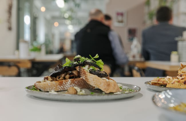 Toasted slices of bread with cooked mushrooms and lettuce on a plate.