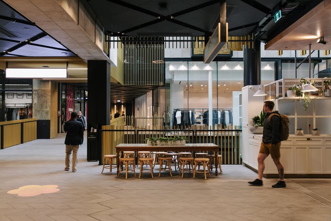 People walking past an empty table inside Commercial Bay Auckland.