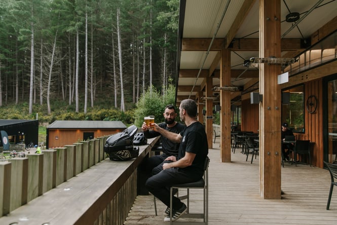 Two men drinking beer on a balcony.