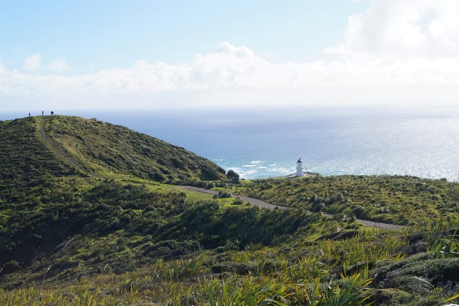 Cape Reinga lighthouse with view of ocean and hills in the background