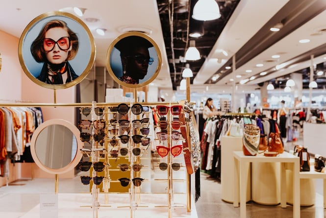 A gold sun glasses rack with a circle mirror.