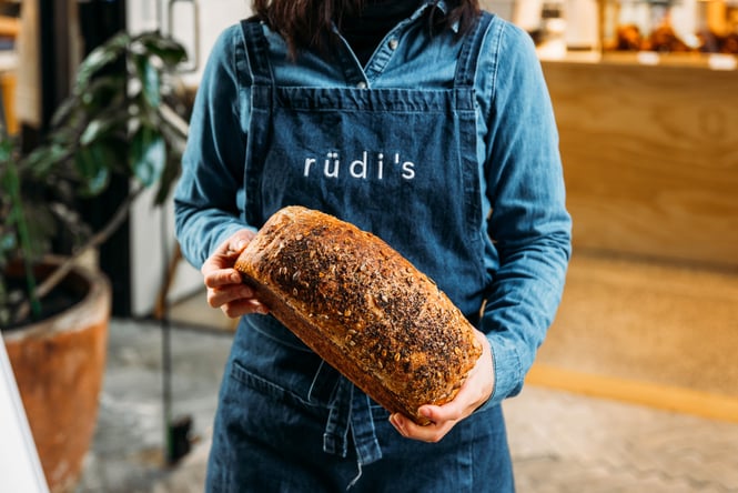 A person holding a loaf of bread at Rudi's in Hamilton.